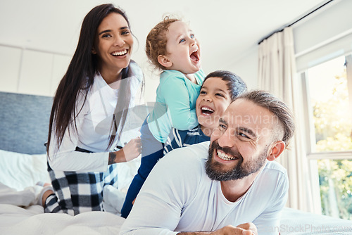 Image of Family, portrait and laughing on bed in house, having fun and bonding together. Comic, love and care of happy father, mother and kids or boys playing, smile and enjoying quality time in home bedroom.