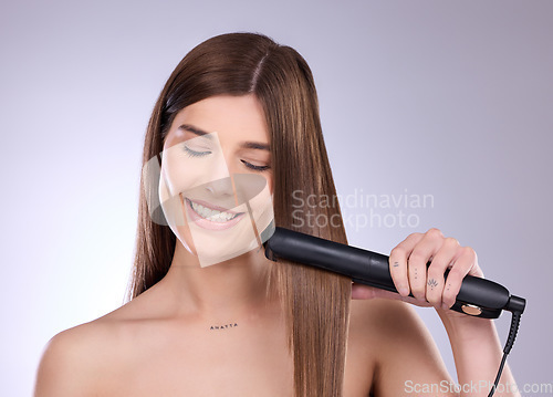 Image of Hair straightener, face and beauty smile of woman in studio isolated on a gray background. Haircare, happy and young female model with flat iron product for salon treatment, balayage or hairstyle.