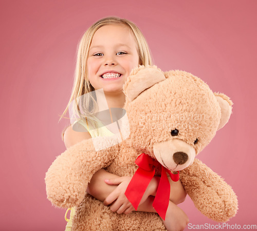 Image of Teddy bear hug, girl smile and portrait with a toy with happiness and love for toys in a studio. Isolated, pink background and a young female child feeling happy, joy and cheerful with stuffed friend