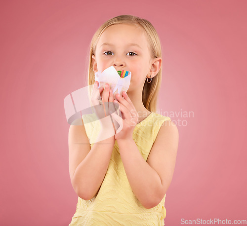 Image of Girl child, cupcake and portrait in studio on a pink background while eating cake. Face of a female kid model with a sweet snack, creativity and paper in hand isolated on color and a gradient space