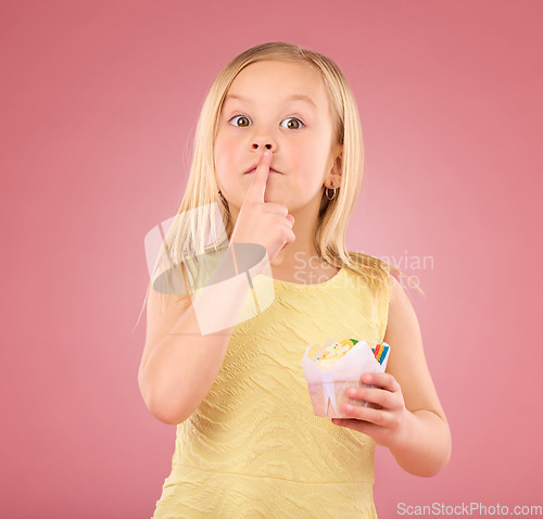 Image of Girl child, finger on lips and cupcake portrait in studio on a pink background for hush and silence. Face of female kid model with cake, secret and sweet snack in hand isolated on color and space