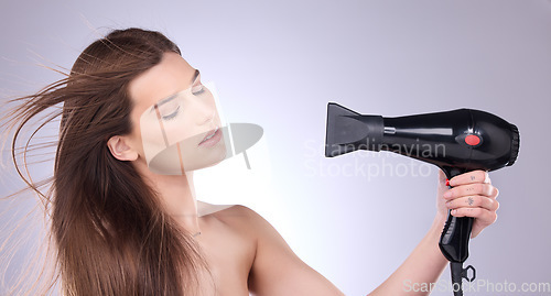 Image of Beauty, blowing and a woman drying her hair in studio on a gray background for grooming or style. Salon, cosmetics and appliance with an attractive young female indoor to blowdry while styling