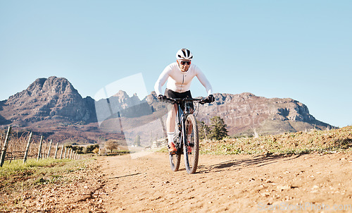 Image of Man, mountains and cycling on trail in nature, countryside and blue sky for triathlon sports in Cape Town. Cyclist, bicycle and off road path outdoor for fitness, bike exercise and energy in sunshine