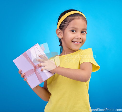 Image of Gift, happy and smile with portrait of girl for celebration, shopping and birthday event. Happiness, surprise and present with child for party, giveaway and products isolated on blue background