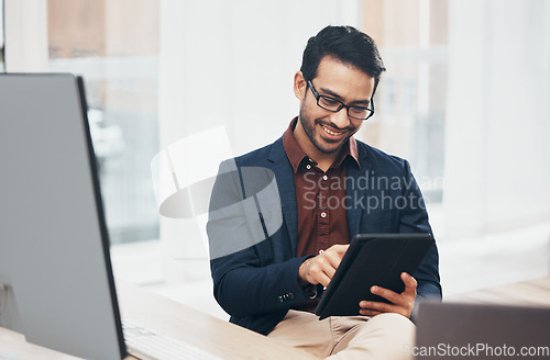 Image of Office, happy Indian man at desk with tablet and computer, reading good news email or successful sales report online. Business, smile and communication with internet, social media or research on web.