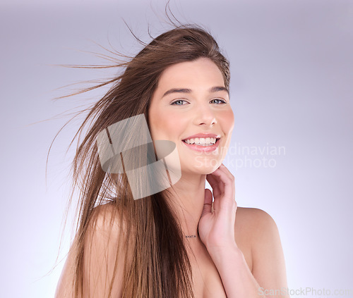 Image of Portrait, hair and wind with a woman in studio on a gray background for haircare or keratin treatment. Shampoo, salon and beauty with an attractive young female model posing in a breeze on a wall