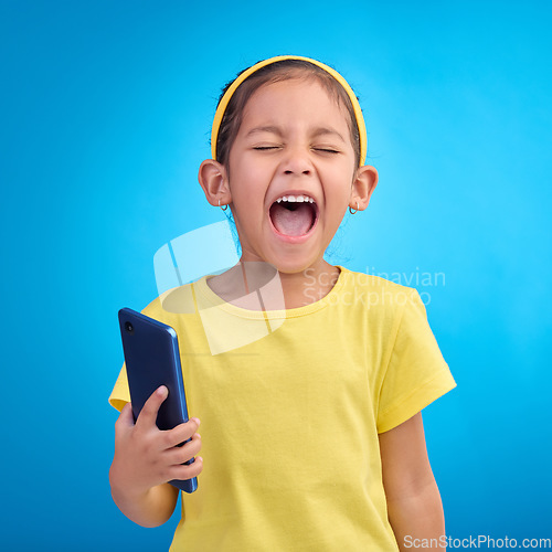 Image of Phone, scream and child on blue background with attitude, upset and lose online game, network or internet. Technology, bad behaviour and face of girl upset, angry and shout with smartphone in studio