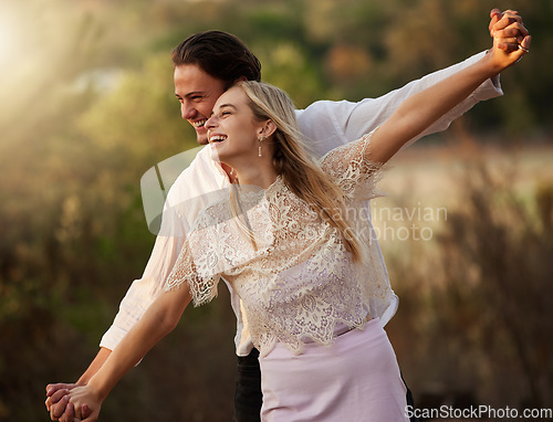 Image of Nature, romance and couple with playful freedom on romantic honeymoon or summer date. Love, woman and man holding hands, flying gesture and happy smile bonding together on weekend at sunset in forest