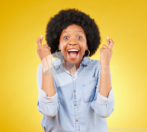 Image of Happy, portrait and fingers crossed by black woman in studio for wish, hope and good luck against yellow background. Face, hands and emoji by excited female with wow, surprised and hopeful gesture