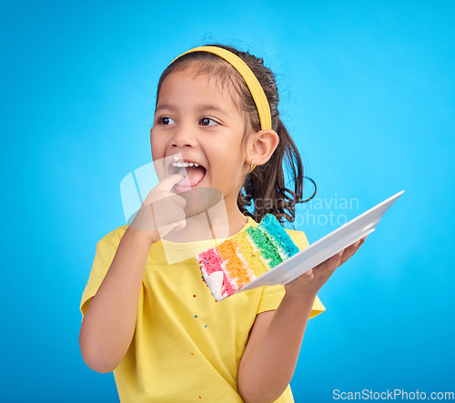 Image of Happy, tasting and girl with cake, excited and cheerful against blue studio background. Young person, Latino female child and kid with dessert, happiness or cheerful with licking finger and celebrate