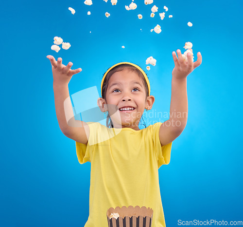 Image of Food, happy and child throw popcorn on blue background for entertainment, movies and cinema mockup. Comic, smile and excited young girl with sweet snack in studio for party, celebration and eating