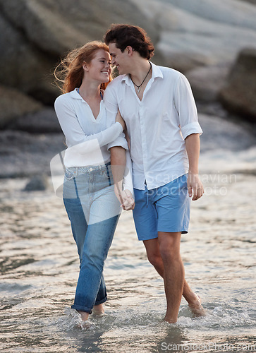 Image of Love, romance and couple in the water at the beach holding hands while on a vacation together. Happy, smile and young man and woman walking in ocean or sea while on romantic weekend trip in Australia