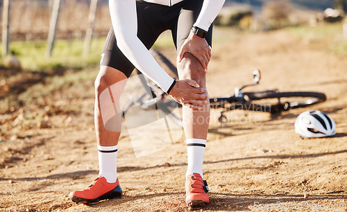 Image of Injury, fitness and man with knee pain while cycling, cramp or inflammation during countryside cardio. Exercise, injured and biker with a sprain after a fall, accident or training for a competition