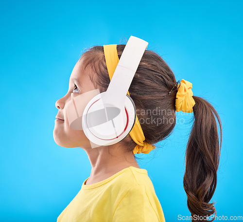 Image of Music, headphones and listening with girl in studio for streaming, mobile radio and audio. Technology, media and youth with profile of child isolated on blue background for natural, happy and songs