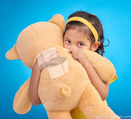 Image of Portrait, hug and child in studio with teddy bear, sweet and innocent on gradient blue background. Face, embracing and child with teddy. hiding and shy, sweet and play while hugging on isolated space