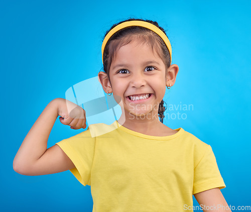 Image of Strong, happy and portrait of a child with muscle isolated on a blue background in a studio. Excited, smile and girl kid showing biceps, arms and power from exercise with confidence on a backdrop