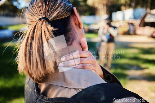 Image of Closeup, neck pain and hand of woman with injury in paintball, sports and training on blurred background. Rear view, back pain and injured girl with accident during sport, workout or match on a field