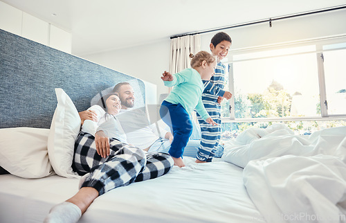 Image of Family, morning and kids jumping on a bed, playing while having fun in the bedroom of their parents. Happy, children or wake up with a brother and sister in a house feeling playful or excited