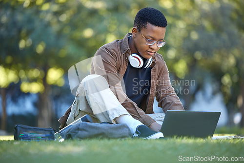 Image of Black man, park studying and laptop work in a campus garden working on web education. Outdoor, happiness and online elearning with a textbook of a student busy with exam study on university grass