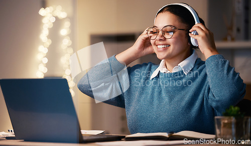 Image of Laptop, music headphones and business woman in home at night streaming radio or podcast after working. Freelancer, remote worker and happy female listening or enjoying audio, song or album in house