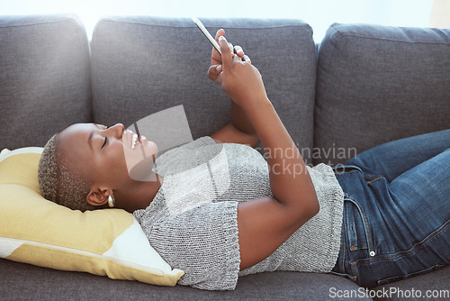 Image of Social media, happy and black woman with a phone on the sofa for communication, chat and internet. Smile, relax and African girl typing on a mobile app for connection, browsing and online search