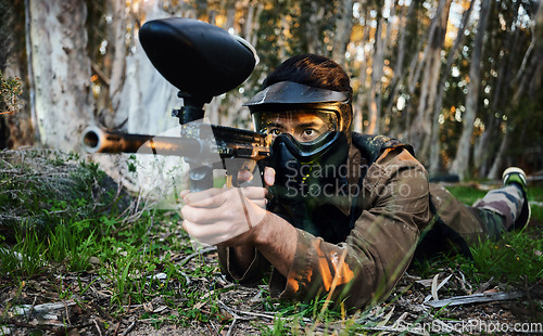 Image of Paintball, gun and army crawl with a sports man on a battlefield for military or war training in nature. Fitness, team building and safety with a male athlete or soldier playing a game outdoor