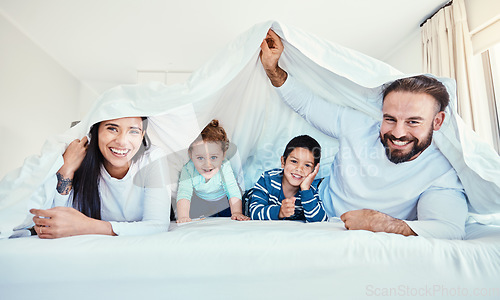 Image of Family, portrait and blanket fort in bed with children and parents, happy and playing in their home. Face, under and sheet by kids with mom and dad in bedroom, fun and waking up, relax and smile