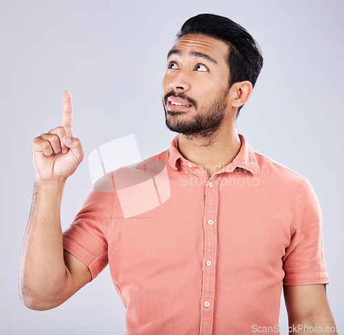 Image of Mockup, Asian man and pointing for space, advertising and happiness against grey studio background. Japan, male and guy with gesture for product placement, branding or gen z with confidence and relax