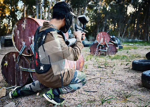 Image of Paintball, gun and shooting with a sports man on a battlefield for military or war training for the army. Fitness, team building and safety with a male athlete or soldier playing a game outdoor