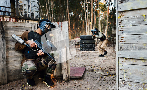 Image of Sports, paintball and man with gun for battle, game or competition outdoors on field. War, military camouflage and male soldier with weapon on shooting range to hide from player in exercise fight.