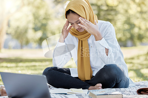 Image of Stress, Islamic and woman student with a headache while studying in a park feeling frustrated and sad outdoors. Laptop, sick and muslim female with a hijab annoyed while learning or reading