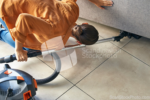 Image of Woman vacuum cleaning under sofa in living room for housekeeping, hygiene maintenance or maid service. Cleaner, electric appliance and flooring, furniture dust and ground tiles and in lounge at home