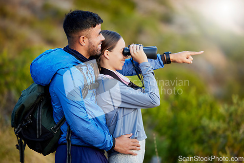 Image of Binoculars, point and a couple bird watching in nature while hiking in the mountains together. Forest, ecology or sightseeing with a man and woman looking at the view while bonding on a hike