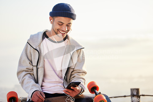 Image of Skateboarder, phone and man streaming music, audio or podcast online and relax after skating with mockup and texting. Skater, skateboard and person listening to mobile radio in sunset on social media