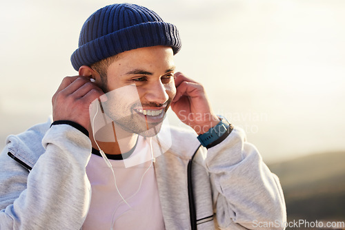 Image of Man with earphones, listening to music and smile outdoor with runner, fitness and motivation with radio streaming. Podcast, technology and exercise at sunset, happy male and running, audio and sport