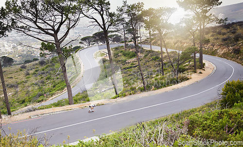 Image of Mountains, skateboard and fitness with man on winding road for training, speed and adventure. Freedom, youth and fast with guy skating in urban street of nature for exercise, wellness and challenge