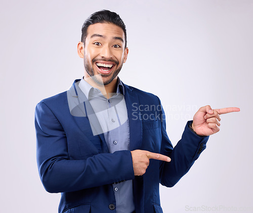 Image of Happy, portrait and man in a studio pointing to mockup for marketing, advertising or product placement. Happiness, smile and male model from India with showing gesture for mock up by gray background.