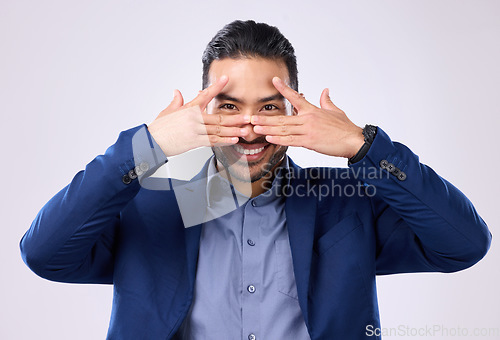 Image of Asian man, business and hands for eyes and smile in studio for motivation and pride while peeking. Happy male model portrait isolated on a gray background as corporate leader with a positive mindset