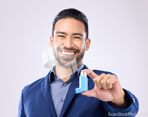 Image of Asthma, pump and portrait with a man in studio on a gray background holding a respiratory device for breathing. Happy, smile and a handsome young male with an inhaler to relieve coughing or wheezing