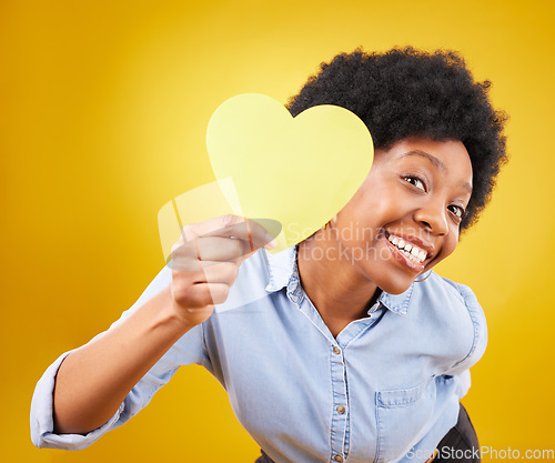 Image of Portrait, heart and social media with a black woman in studio on a yellow background for love or affection. Emoji, shape and romance with an attractive young female feeling excited for valentines day