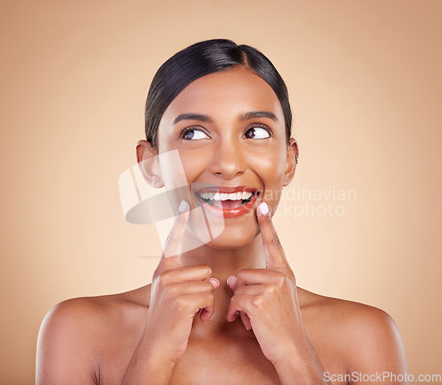 Image of Indian woman, skincare and hands for thinking in studio with face, smile and wellness by background. Young asian model, girl and cosmetics for natural skin glow, aesthetic or happiness for idea
