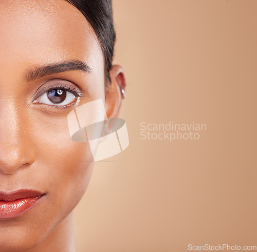 Image of Portrait, beauty and mockup with a model woman in studio on a beige background to promote skincare. Face, eye and mock up with an attractive young female posing for cosmetics or luxury wellness