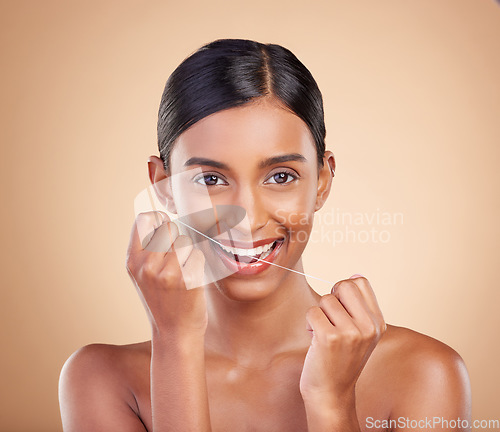 Image of Portrait, dental floss and cleaning with a model woman in studio on a beige background to promote oral hygiene. Face, mouth and teeth with an attractive young female posing for a dentist product