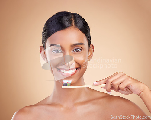 Image of Portrait, toothbrush and toothpaste with a model woman in studio on a beige background for dental or oral hygiene. Face, mouth and dentist with an attractive young female cleaning or brushing teeth