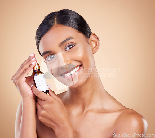 Image of Portrait, beauty and serum with a model woman in studio on a beige background to promote skincare. Face, product and antiaging with an attractive young female posing for cosmetics or luxury wellness