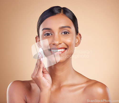 Image of Portrait, beauty and cotton swab with a model woman in studio on a beige background to promote skincare. Face, skin and exfoliate with an attractive young female posing for luxury cosmetics