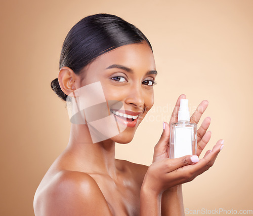 Image of Portrait, product and serum with a model woman in studio on a beige background for beauty or skincare. Face, bottle and antiaging with an attractive young female posing for luxury cosmetics