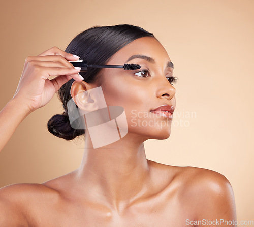 Image of Makeup, product and woman with mascara for eyelashes isolated on a studio background. Thinking, cosmetology and Indian girl with a brush for applying cosmetics, pomade or treatment to lashes