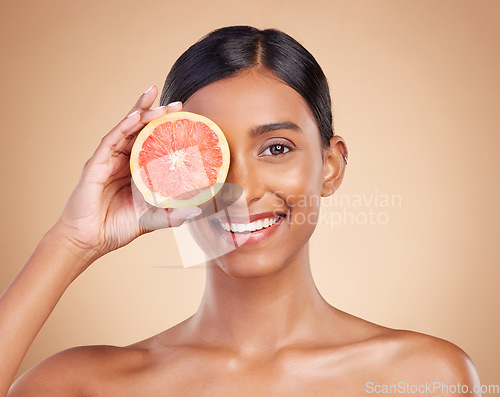 Image of Portrait, beauty and grapefruit with a model woman in studio on a beige background to promote skincare. Face, eye and fruit with an attractive young female posing for natural or organic cosmetics