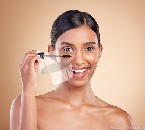 Image of Portrait, beauty and mascara with a model woman in studio on a beige background to promote makeup. Face, eye and product with an attractive young female posing for cosmetics or luxury wellness